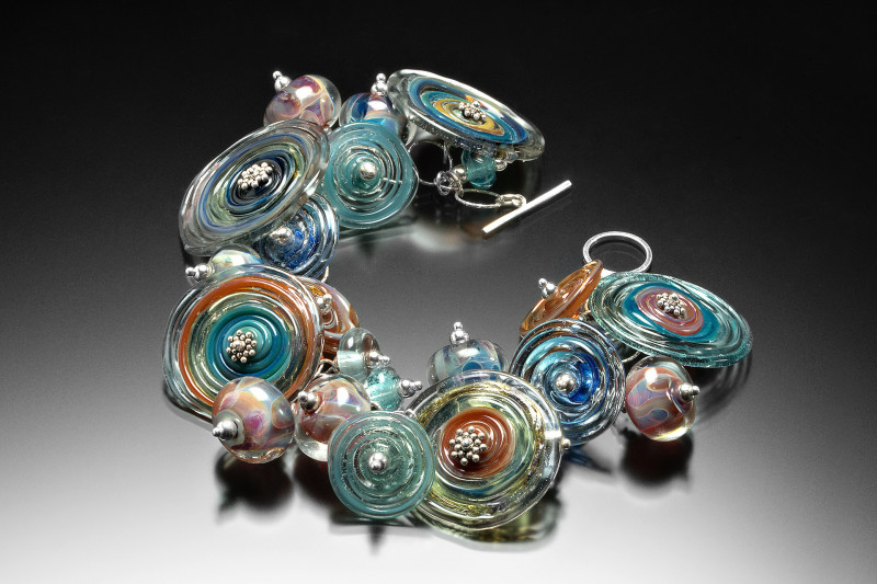 Bracelet decorated with large multicolored glass spiraled discs with silver balls in the center. Created by Jessica Keemer.