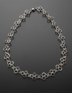 Silver necklace shaped into sets of intersecting infinity symbols, with lobster claw clasp. Created by Mary Beth Nardy