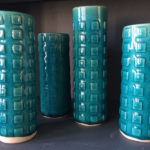 Four tall blue cylinders with square accents created by Dorrie Papademetriou