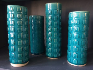 Four tall blue cylinders with square accents created by Dorrie Papademetriou