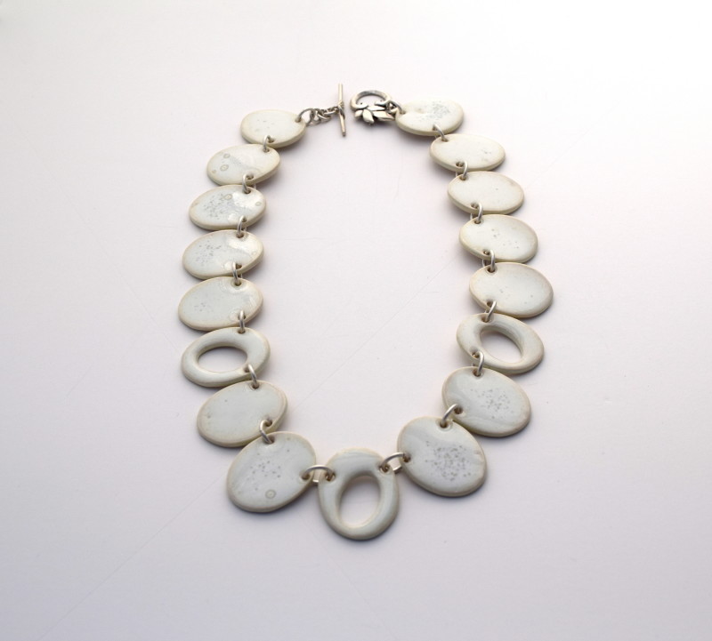 Necklace of seventeen white porcelain ovals connected by small silver links and toggle clasp. Created by Kyougn-Joa Park.