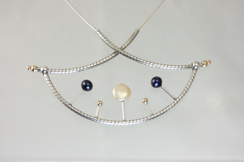 Necklace created by Gina Romano showcasing a pendant of silver tubing decorated with gold, pearl, and iridescent blue spheres