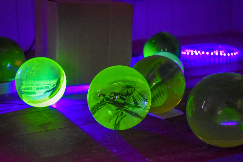 "Emanation 2019" Artist Jo Yarrington's uranium glass orbs glow green under blacklight in a dark room.