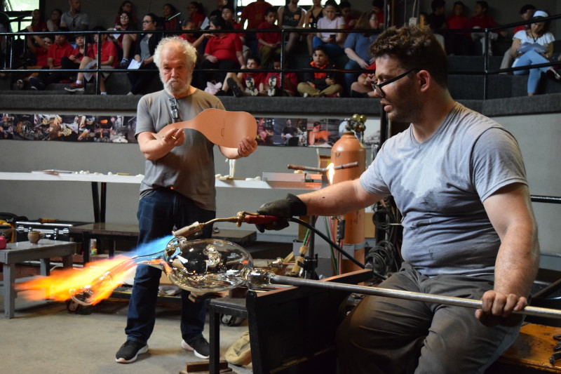 Spectators watch "Emanation 2019" Artist Allan Wexler and WheatonArts Glass Artist Skitch Manion work together.