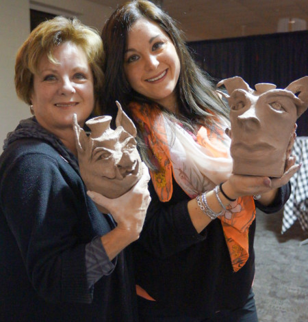 Two women posing to show off their sculpted face jugs