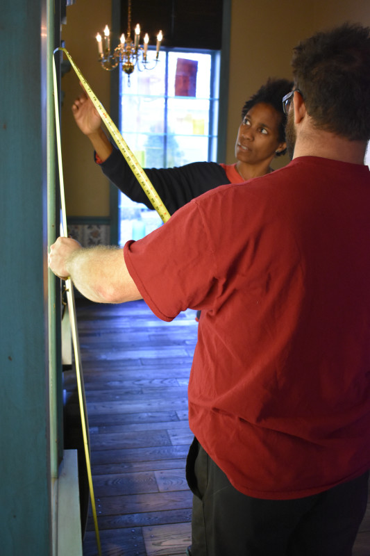 "Emanation 2019" Artist Karyn Olivier and WheatonArts Glass Artist measure a display case in the Museum of American Glass.