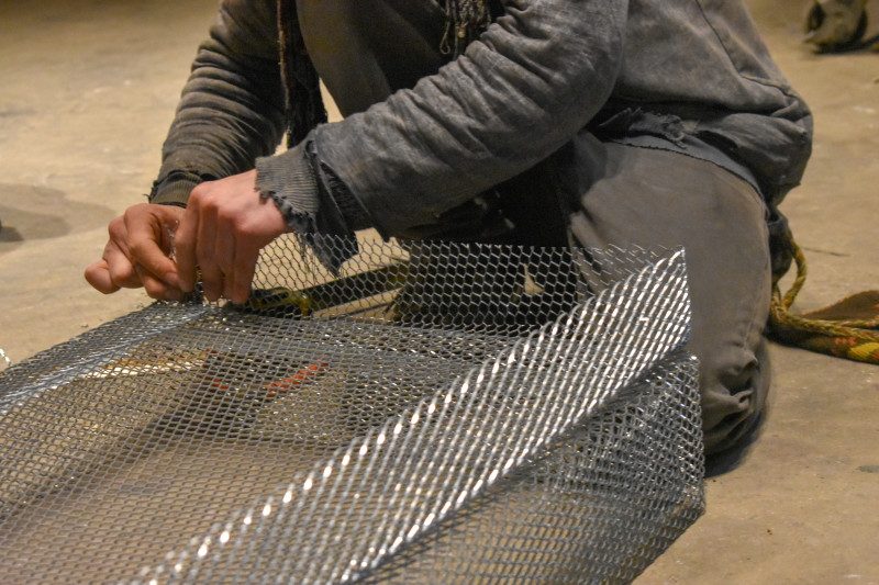 Closeup of hands working carefully to form rectangular boxes out of chicken wire.