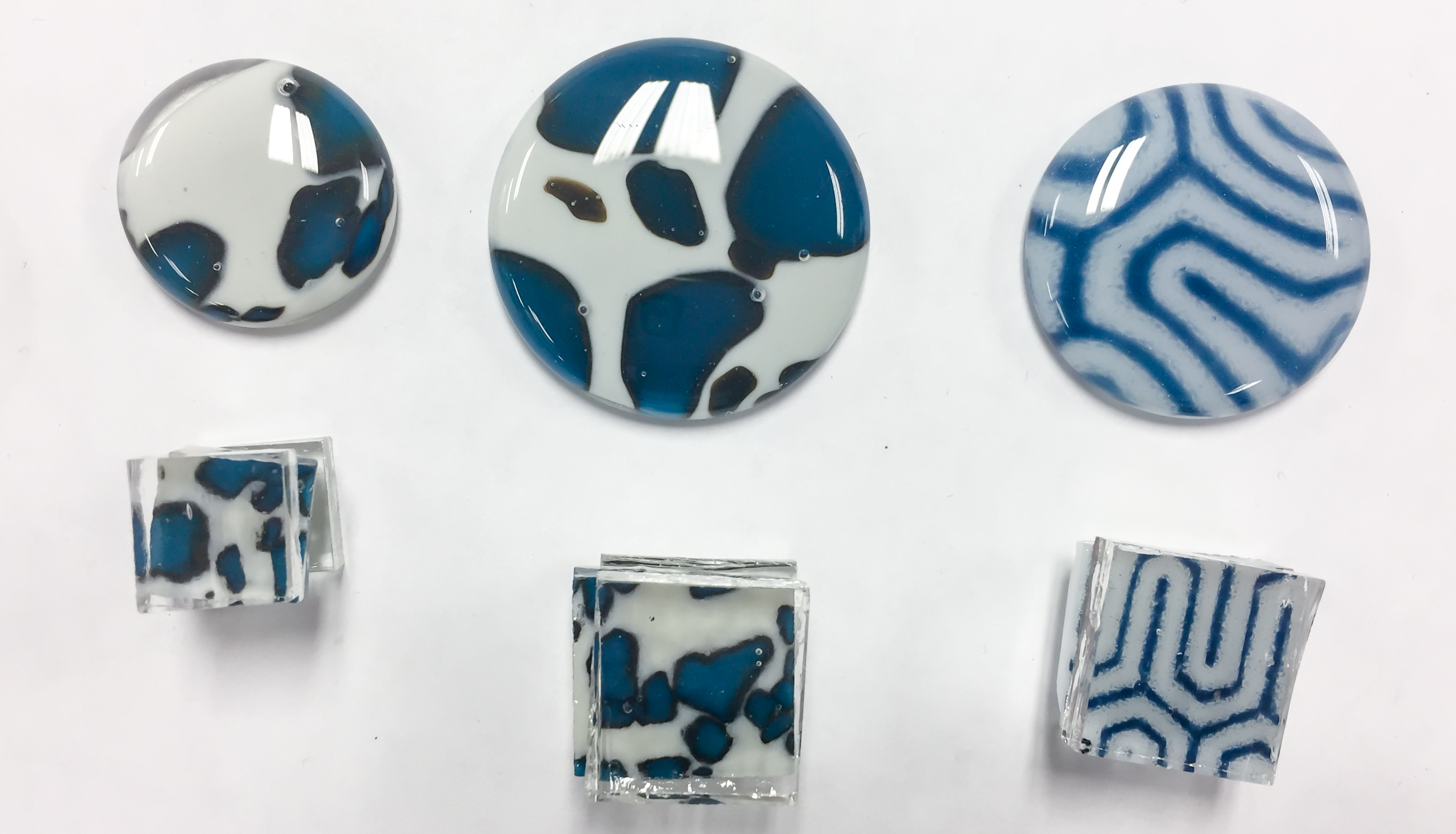 Circle and square glass fused pendants of various sizes, with blue and white designs of spots and lines.