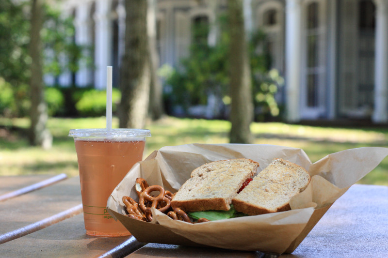 Sandwich and pretzels in a small box with a refreshing drink on the left from the GateHouse Cafe