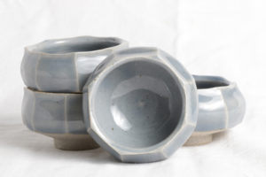 Four matching, cool gray octagonal cups with thin white lines separating each side. Created by Samantha Bartlett