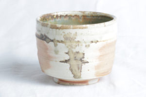 A white ceramic cup, strategically mixed with tans and soft greens. Created by Samantha Bartlett.