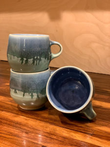 Matching blue and white mugs. Two are stacked and the third is on its side, its deep blue inside facing the camera. Created by Samantha Bartlett.