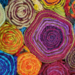 A closeup of several colors of fiber wrapped into tight circles and put together to create a piece.