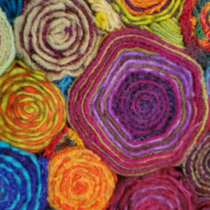 A closeup of several colors of fiber wrapped into tight circles and put together to create a piece.
