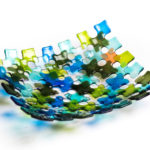 Blue, orange, green, teal, and white bowl by Stephanie Baness formed with small overlapping glass squares of each color