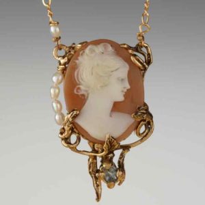 detail of a golden necklace with a cameo of a woman on an orange stone pendant.