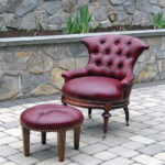 An elegant maroon chair and footrest on a stone floor. Created by Olya Bragger