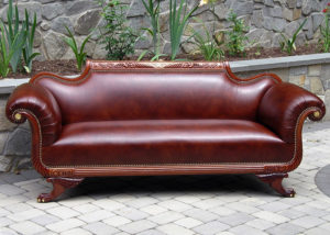 A long rich red sofa with armrests that curl out to the sides. Created by Olya Bragger