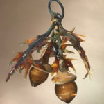 Hanging flamework sculpture by Stephen Brucker of orange oak leaves surrounding two large acorns