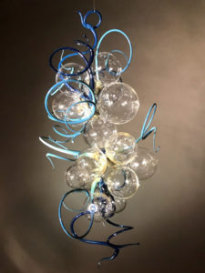 Hanging flamework sculpture by Stephen Brucker of several clear orbs with protruding light and dark blue spirals