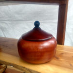 Small red wooden container with a deeper red wooden lid by Thomas Cambria