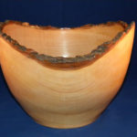 A wooden vessel by Thomas Cambria with an organic textured rim that dips down in the center