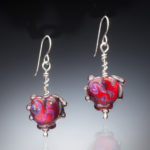 Dangling earrings by Sharon Carlucci. Darngling from each earring is a red heart with purple swirls within it.