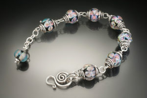 Bracelet by Sharon Carlucci with a silver chain and matching glass beads with iridescent floral designs.