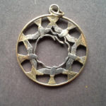 Metal coin pendant carved by Allan Feinberg depicting five birds fly in a circle around the inside edge, creating a circle of negative space in the innermost center