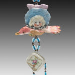 found object necklace by Hilary Greif, a porcelain doll head over a small pink porcelain bird with dangling blue beads.