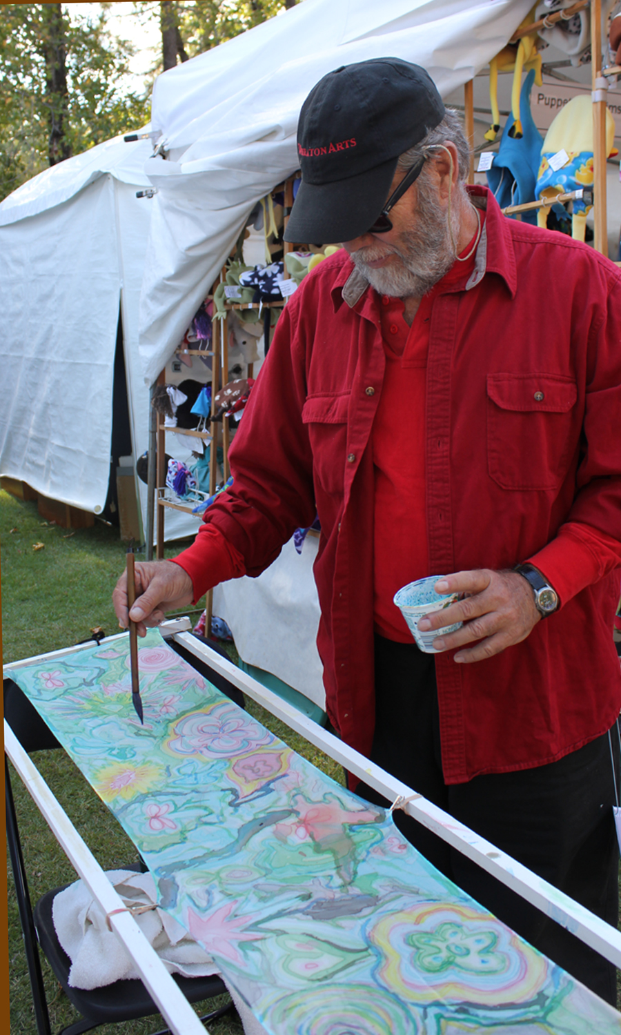 Man in red painting a silk scarf.