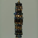 Pendant made of a collection of gold, iridescent purple, and black beads. Created by Naomi Johnson
