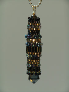 Pendant made of a collection of gold, iridescent purple, and black beads. Created by Naomi Johnson