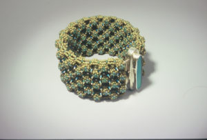 Green and blue beaded bracelet by Naomi Johnson with a tall thin blue glass piece encased in silver in the center