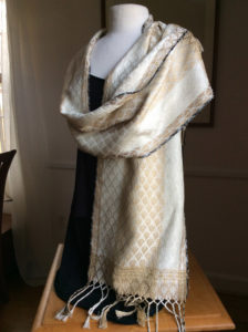 A thick latte brown and white scarf loosely wrapped around a white mannequin form. Created by Maureen Kamerick