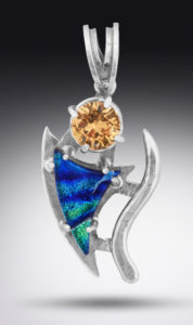 A silver pendant by Paul Lorber with a yellow gemstone and a swooping blue triangle stone dangling below