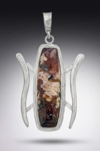 A silver pendant by Paul Lorber cradling a smooth brown oval gemstone