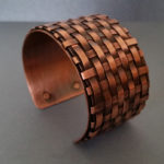 Copper cuff bracelet with a woven pattern. Created by Kim Lyons