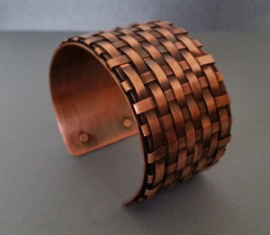 Copper cuff bracelet with a woven pattern. Created by Kim Lyons