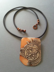 An orange necklace by Kim Lyons with celtic knot designs