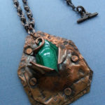 Textured copper pendant with a partially hidden green stone. Created by Kim Lyons
