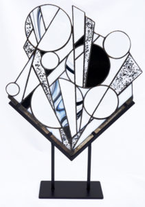 Copper foil and glass fashioned into a geometric piece of art made up of lines and circles.