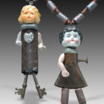 two found object necklaces by Hilary Greif, each having a porcelain doll head and arms with metal bodies and legs