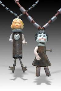 two found object necklaces by Hilary Greif, each having a porcelain doll head and arms with metal bodies and legs