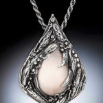 Semiprecious stone held by a droplet shape pendant carved with botanical elements. Created by Judith Hearney