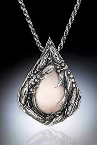 Semiprecious stone held by a droplet shape pendant carved with botanical elements. Created by Judith Hearney