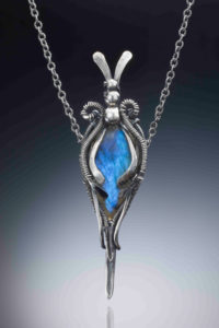 Silver color pendant with a small rabbit head on the top, holding a rich blue semiprecious stone. Created by Judith Hearney