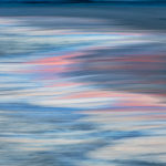 Photograph by Frederick Ballet of waves closeup with white and pink reflections on the water.