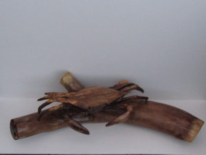A crab on a log, both carved out of wood. Created by Gilbert Carey.