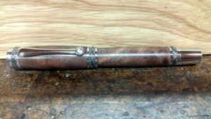 A closeup of a smooth wooden pen with a small gemstone on the cap. Created by Thomas Ferrie.